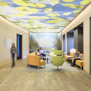 Peaceful waiting area of children's pain clinic with murals of nature on wall and ceiling with a parent and children