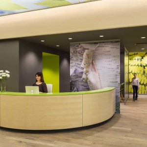 Curved wood reception desk in waiting room of children's clinic with people