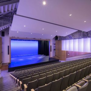 New auditorium in middle school with colorful lighting on walls and hanging fabric panels