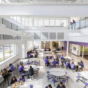 Bright two story high school lunchroom seen from above with students eating