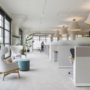 New office space in older building showing cubicles and two wing back chairs with person