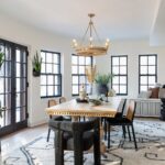 A black and white dining room with black windows and black and white area rug