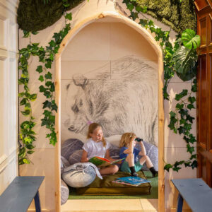 A young boy and girl reading and playing in a make believe cave in the children's play area of a museum