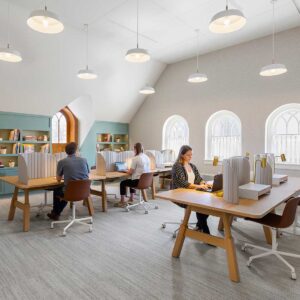 People working in library of historic mansion museum with built-in bookcases and arch top windows