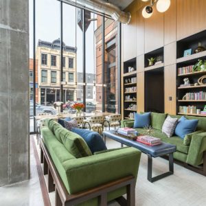 Tall two story lobby of apartment building with living room area and built-in bookcases