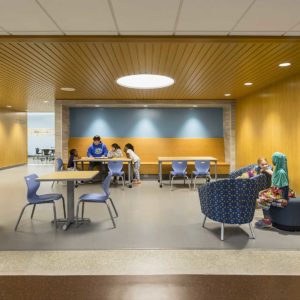 Students and teacher talking in new gathering and seating area for students in grade school