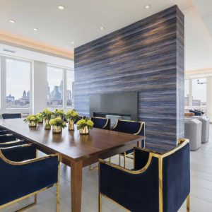 Upper floor lounge in new apartment building showing long table next to fireplace and multiple floor to ceiling windows