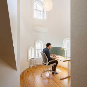 A man working at a desk in small office area in a turret of older museum building